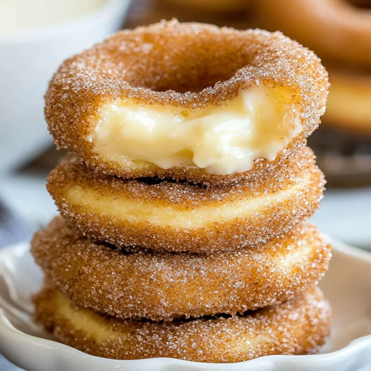 Stack of churro cheesecake cookies with creamy cheesecake filling, coated in cinnamon sugar and served in a white bowl.