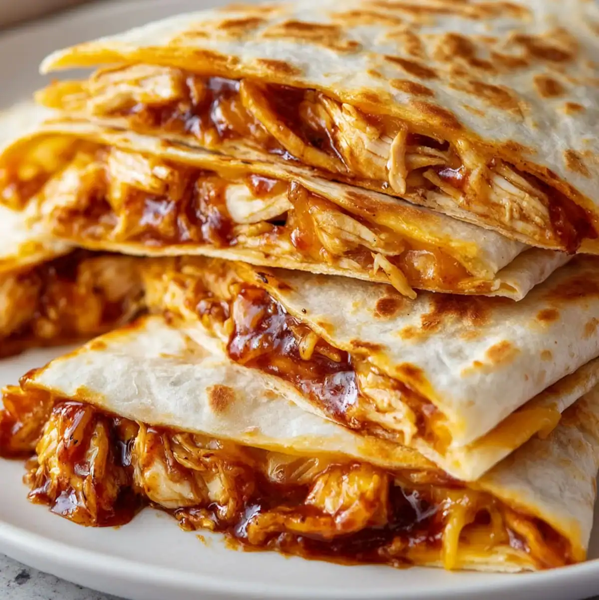 Stack of BBQ Chicken Quesadillas with golden brown tortillas and gooey cheese.