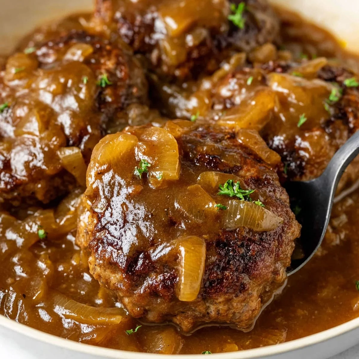 Hamburger Steak and Gravy – Easy Family Dinner Recipe 83 Hamburger steak and gravy simmering in a skillet with onions and rich brown gravy.