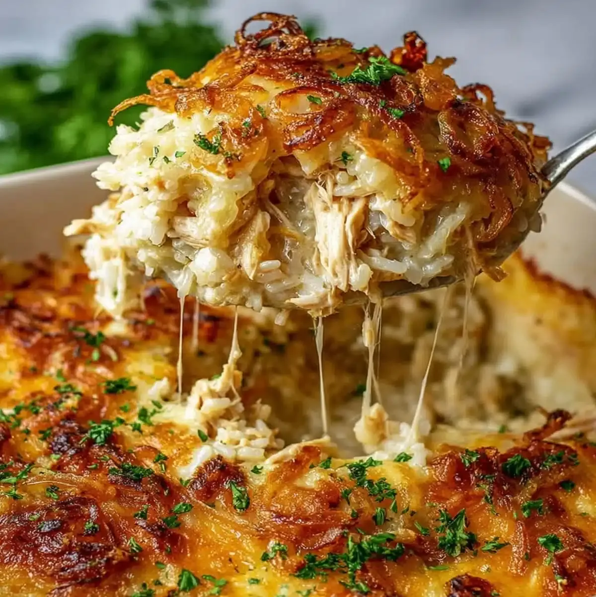 Cheesy French Onion Chicken being served from a baking dish with melted cheese and caramelized onions