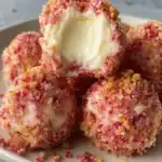 Close-up of no-bake strawberry cheesecake truffles with creamy cheesecake center and crunchy strawberry Oreo coating.