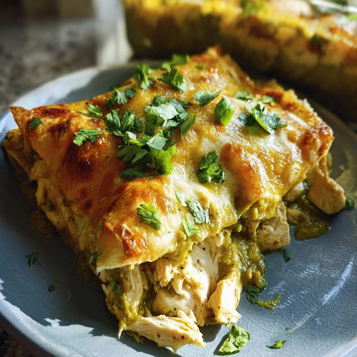 Close-up of Green Chile Chicken Enchiladas topped with melted cheese and cilantro on a plate