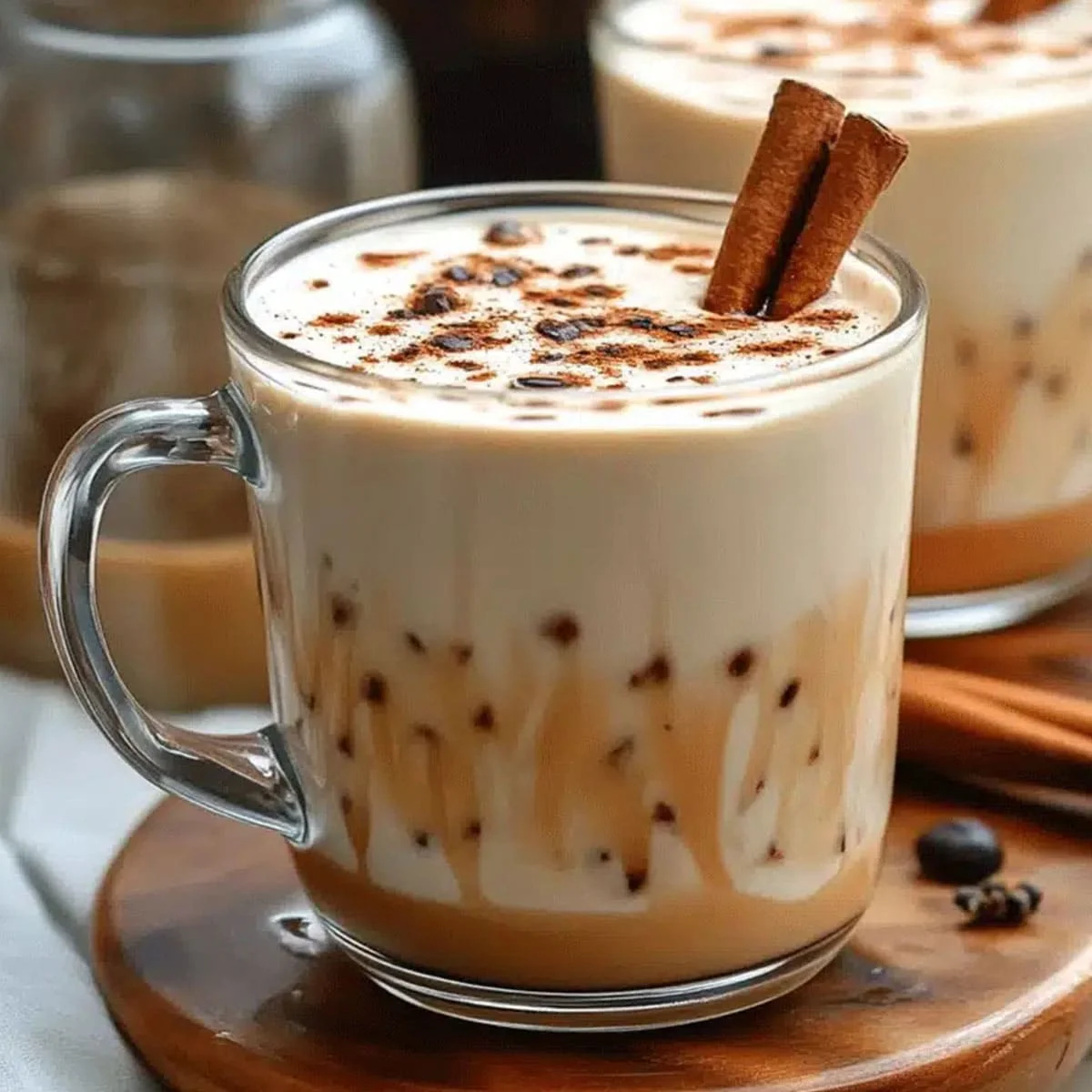 Chilled chai tea latte with cinnamon sticks and chocolate swirl served in a glass mug