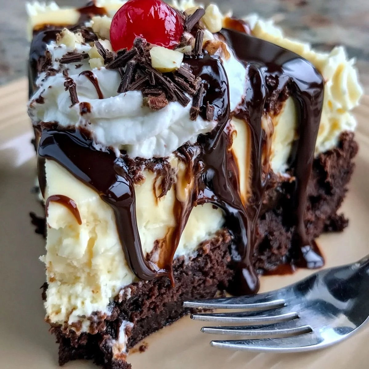 Hot Fudge Sundae Brownie Cheesecake with whipped cream, chocolate fudge drizzle, brownie crust, and cherry on top
